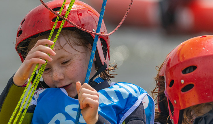 closeup of young child wearing a helmet pulling on rigging