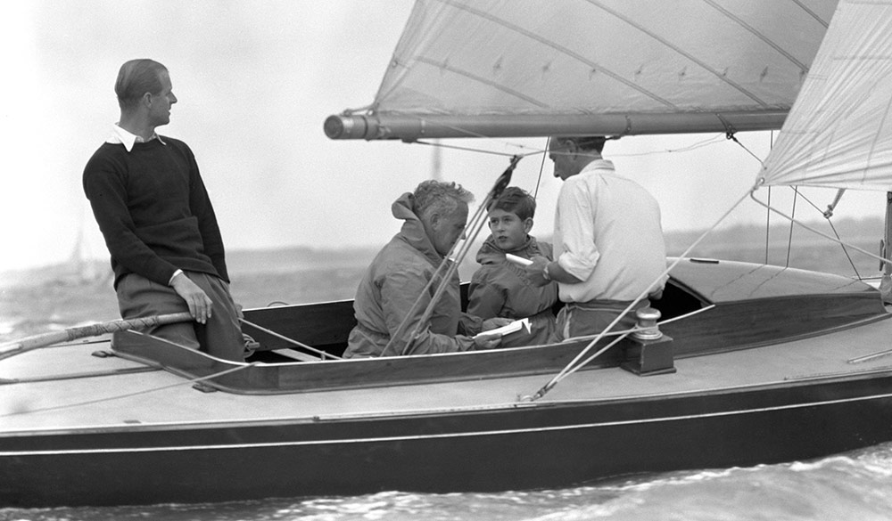 Black and white image of a young king Charles in a dinghy with his father, Philip, duke of Edinburgh.