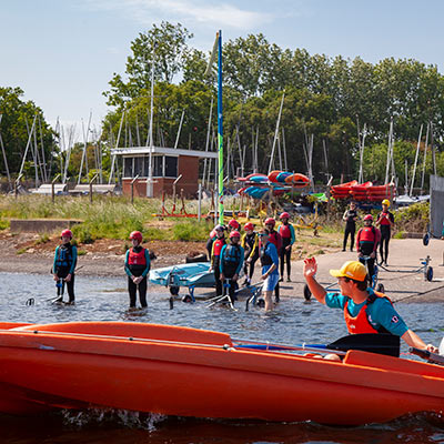 a group of children preparing to go sailing at a club on a lake