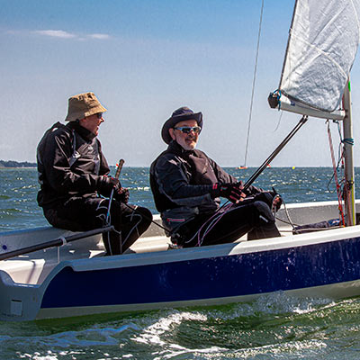 two sailors sailing a dinghy on the open sea