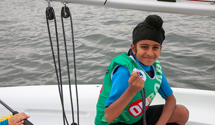 young child posing for picture while sailing a dinghy