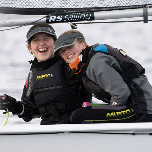 posed shot of two smiling children in an RS sailing dinghy