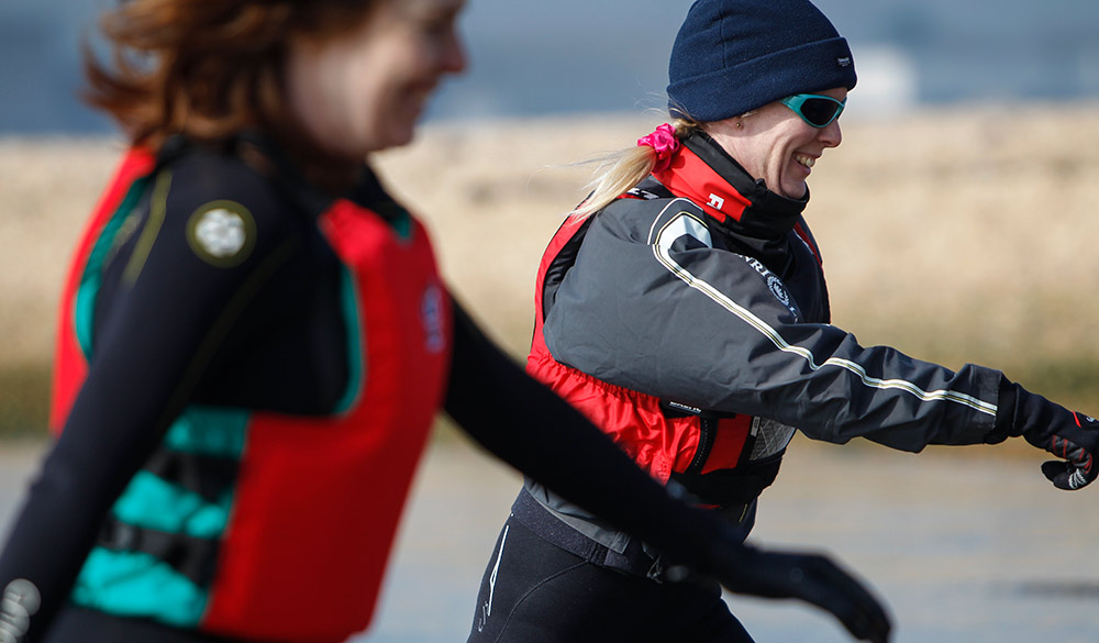 Women walking to the water wearing hats and life jackets