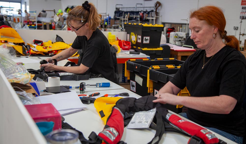 Two women sat a desk carrying out lifejacket servicing 