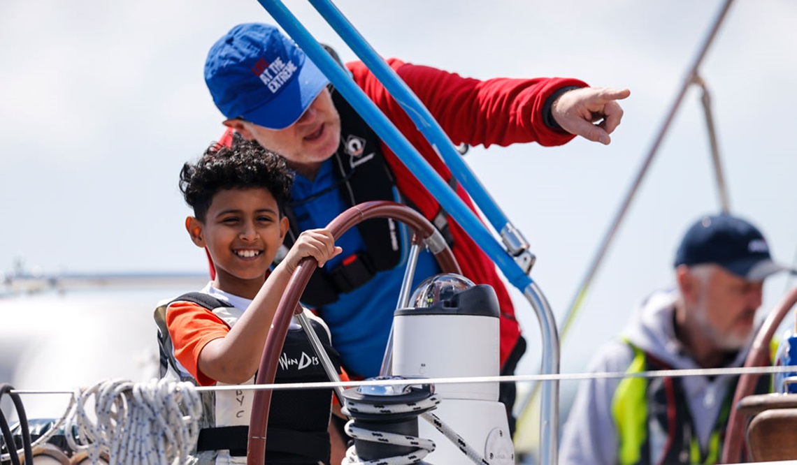 wide shot of child steering a boat with supervision 