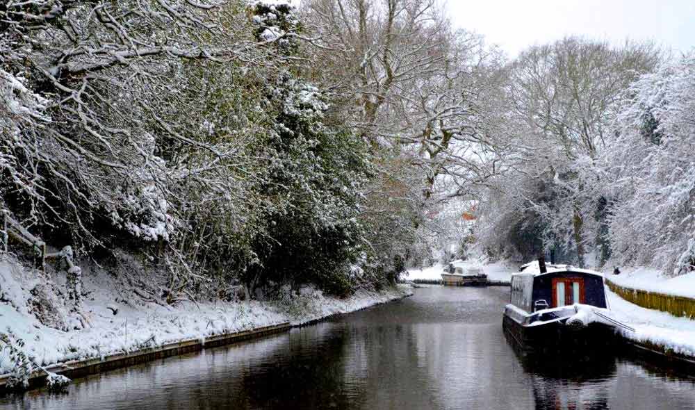 Snowy river with canal boats slowly moving