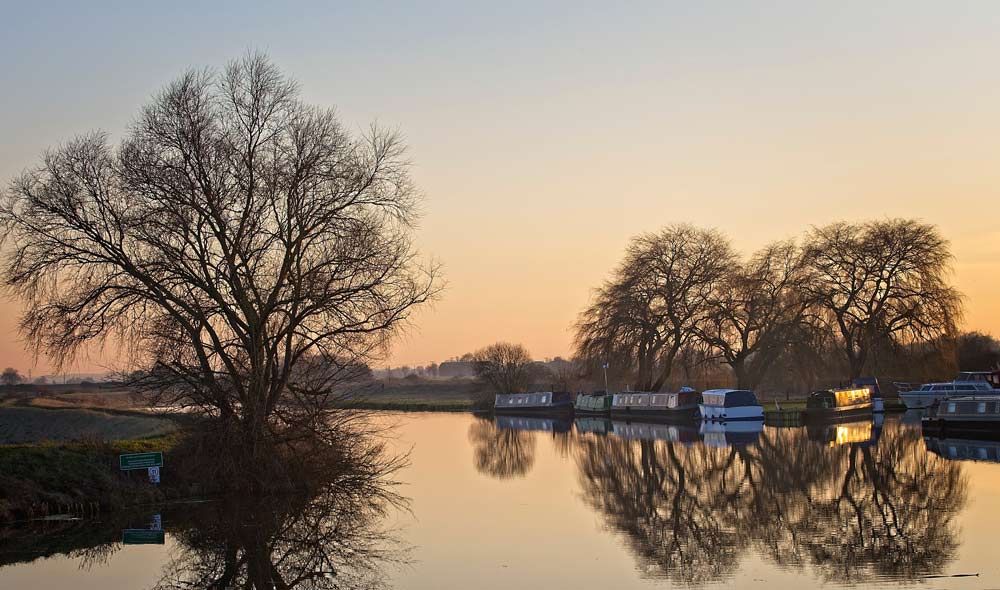 canal boats lined up on the river during a winter sunrise 