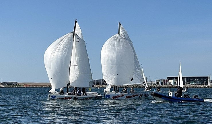 Close racing between two teams flying spinnakers downwind with a RIB alongside and blue skies at the RYA Marlow Ropes Women's Match Racing Championship.