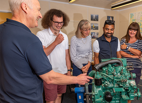 Group of students stood around diesel engine on an RYA Diesel Engine course